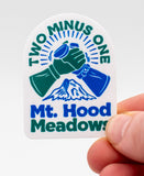 Hand holding a white arch shaped sticker with 2 hands high five-ing. The text says, "Two Minus One" Across the arch and 
"Mt. Hood Meadows" at the bottom.