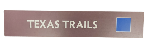 Wooden trail sign with the text, 'Texas Trails' and a blue square icon