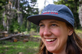 Person wearing a cap with 'Mt. Hood Meadows Avalanche Dogs' text in a forest setting