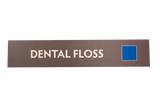 Brown rectangular sign with, 'Dental Floss' text and a blue square logo
