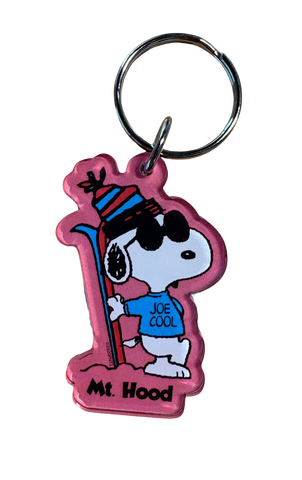 Keychain with a cartoon character holding ski's on a pink background