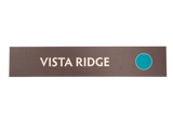 Rectangular brown sign with 'Vista Ridge' text and a green circle icon